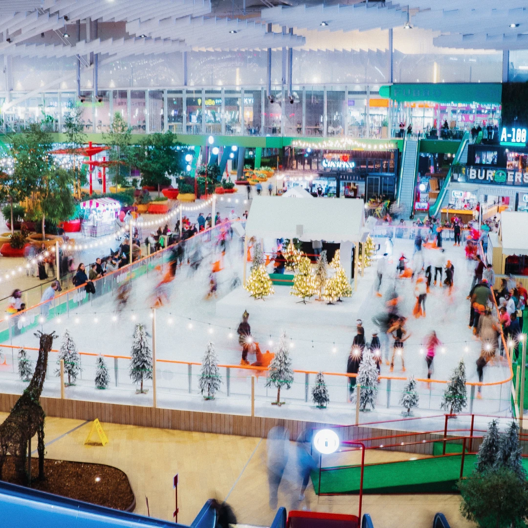 Pista de patinaje sobre hielo cubierta con decoración navideña dentro de un centro comercial